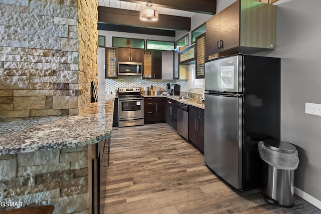 kitchen featuring appliances with stainless steel finishes, light stone countertops, sink, and dark brown cabinets