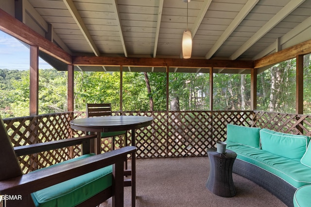 sunroom with lofted ceiling with beams and a healthy amount of sunlight