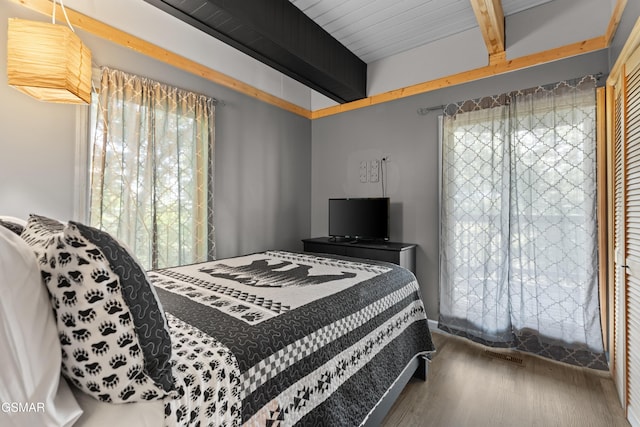 bedroom featuring hardwood / wood-style flooring and beamed ceiling