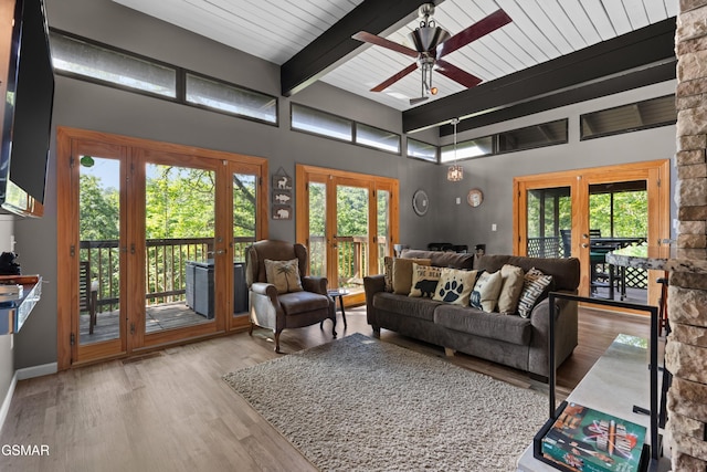 living room featuring ceiling fan, a towering ceiling, french doors, beamed ceiling, and light wood-type flooring