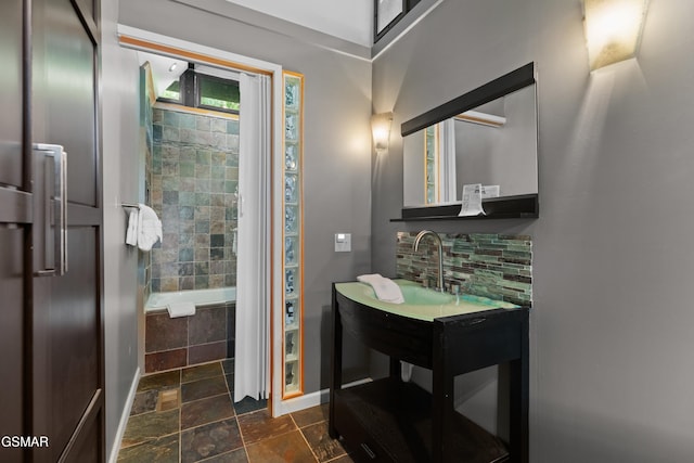 bathroom featuring tasteful backsplash, vanity, and a relaxing tiled tub