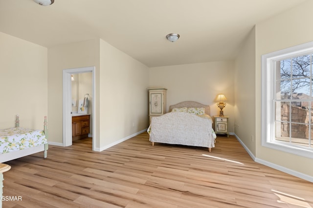 bedroom featuring connected bathroom and light hardwood / wood-style floors