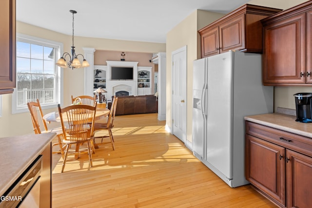 kitchen featuring a notable chandelier, light hardwood / wood-style floors, white fridge with ice dispenser, and hanging light fixtures