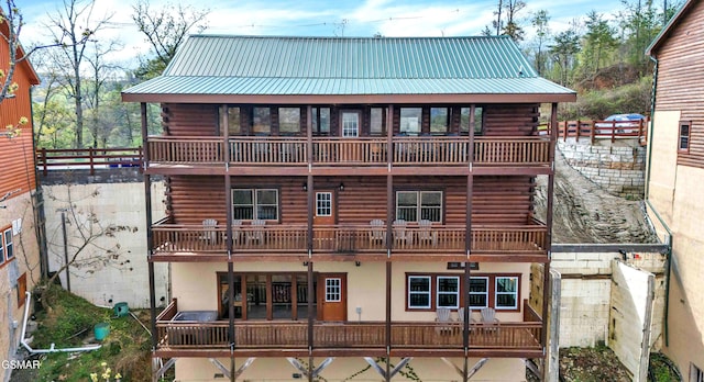 back of property featuring metal roof, a standing seam roof, and log exterior