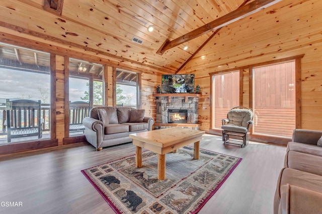 living area with wood walls, a fireplace, beamed ceiling, and wooden ceiling
