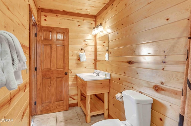 bathroom featuring toilet, wooden walls, tile patterned flooring, and vanity