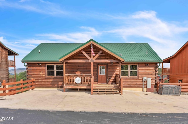 log-style house featuring a patio area, metal roof, and log exterior