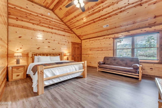 bedroom featuring light wood-type flooring, visible vents, wood ceiling, lofted ceiling, and wooden walls