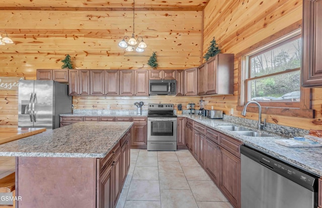 kitchen featuring light tile patterned floors, light stone countertops, wood walls, a sink, and stainless steel appliances