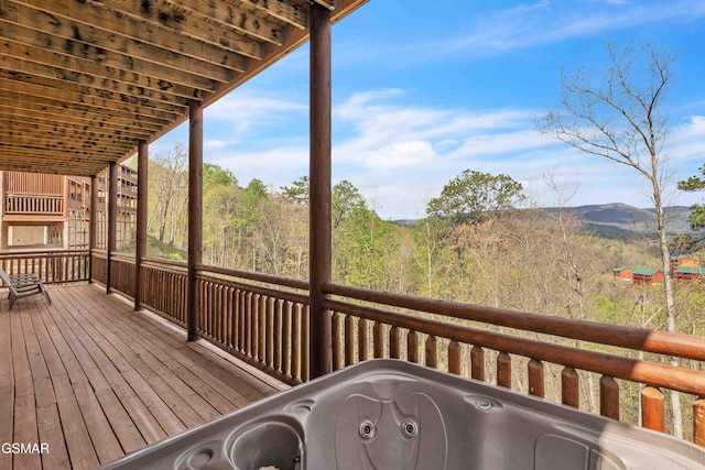 wooden deck featuring a forest view and a hot tub
