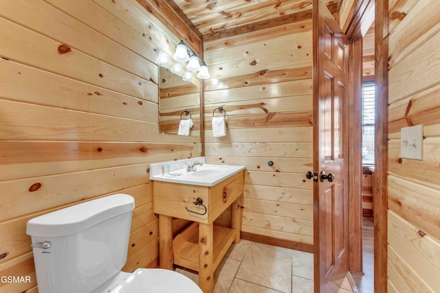 bathroom featuring wood walls, toilet, vanity, and tile patterned floors