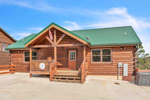 view of front of property with cooling unit, a patio, metal roof, and log exterior