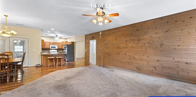 3351 Line Springs Rd, Sevierville, TN 37862 - unfurnished living room with wooden walls, a chandelier, wood finished floors, and a ceiling fan
