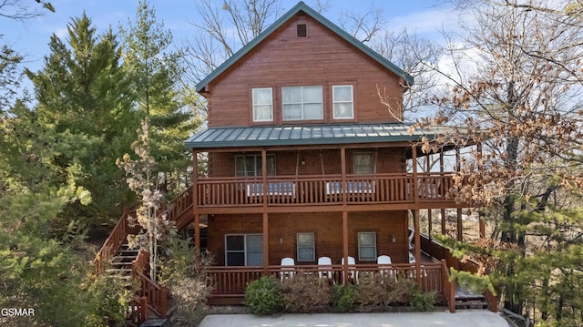 chalet / cabin featuring a standing seam roof, stairs, metal roof, and covered porch