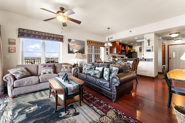 living room with ceiling fan with notable chandelier, baseboards, and hardwood / wood-style flooring