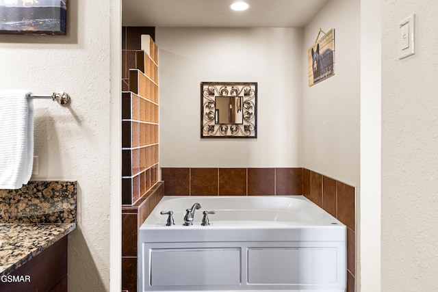 full bath featuring vanity and a garden tub