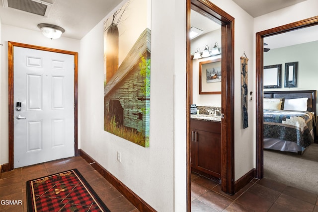 entryway featuring dark tile patterned flooring, baseboards, visible vents, and a sink