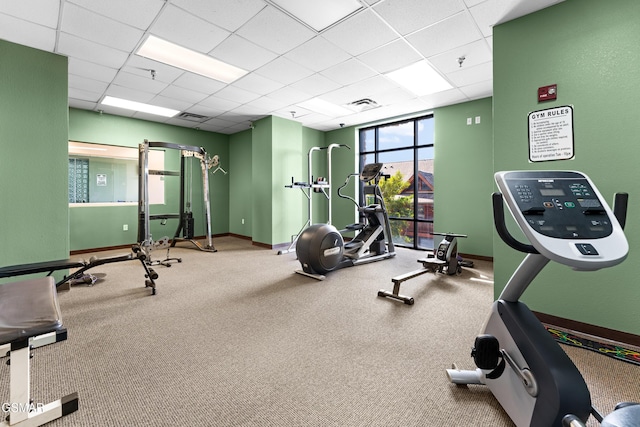 exercise room featuring a paneled ceiling, visible vents, and baseboards