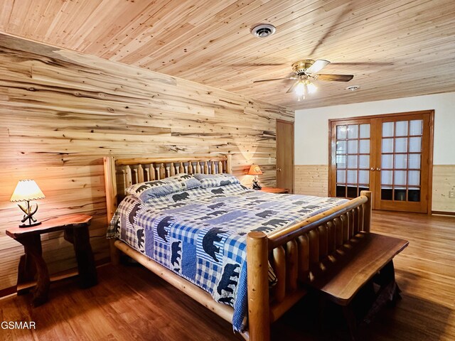 bedroom featuring french doors, ceiling fan, wooden ceiling, hardwood / wood-style floors, and wood walls