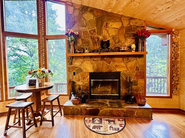 living room with a stone fireplace, wooden ceiling, lofted ceiling, and hardwood / wood-style flooring