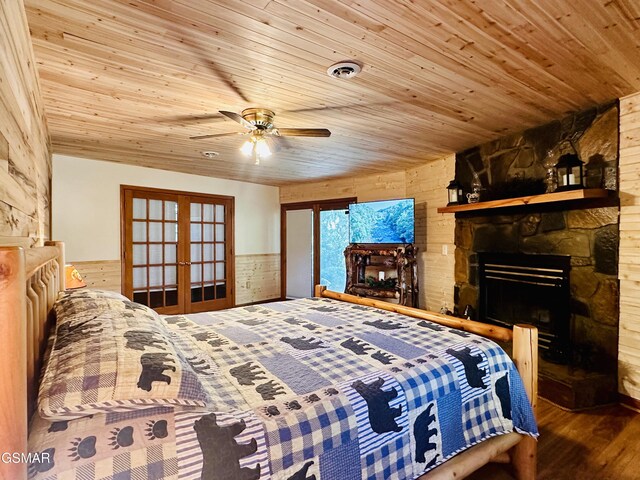 bedroom featuring french doors, wooden walls, ceiling fan, a fireplace, and wood ceiling