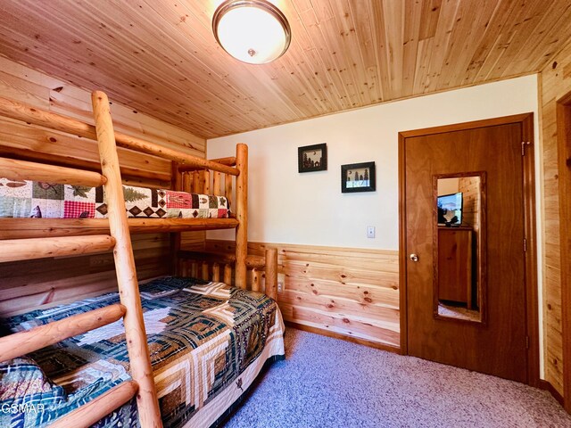 bedroom with carpet, wooden ceiling, and wood walls