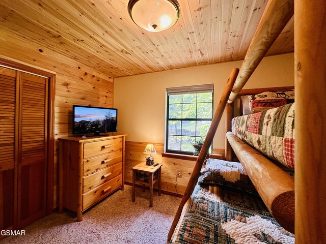 carpeted bedroom with wood walls, a closet, and wood ceiling