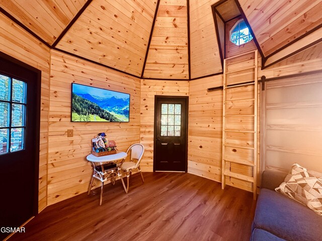 living area featuring wood-type flooring, vaulted ceiling, wooden ceiling, and wood walls