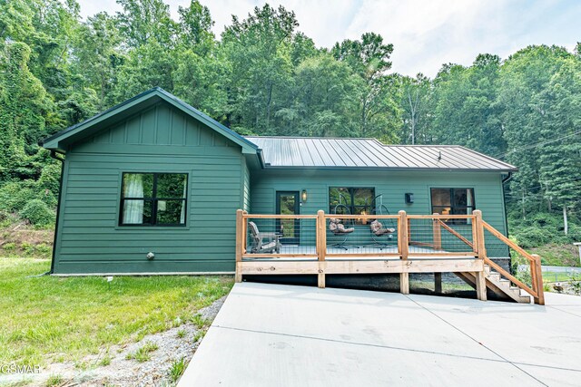 706 Kelly St, Gatlinburg, TN 37738 - view of front of home with a deck, a metal roof, board and batten siding, and a view of trees