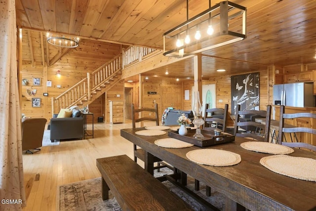 dining space with wood walls, vaulted ceiling, light wood-type flooring, wood ceiling, and a chandelier