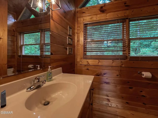 bathroom with vanity, toilet, lofted ceiling, and wood walls