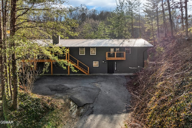exterior space with stairs, a chimney, metal roof, and a forest view