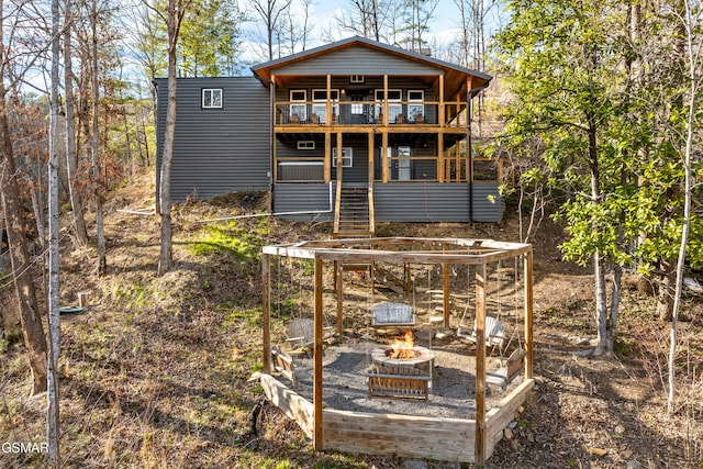 rear view of house with a fire pit and a balcony