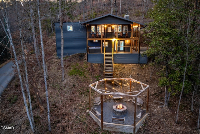 back of property with stairs, a fire pit, and a balcony