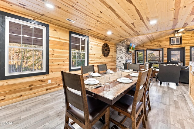 dining space with wood walls, lofted ceiling, wood ceiling, and light wood-style flooring
