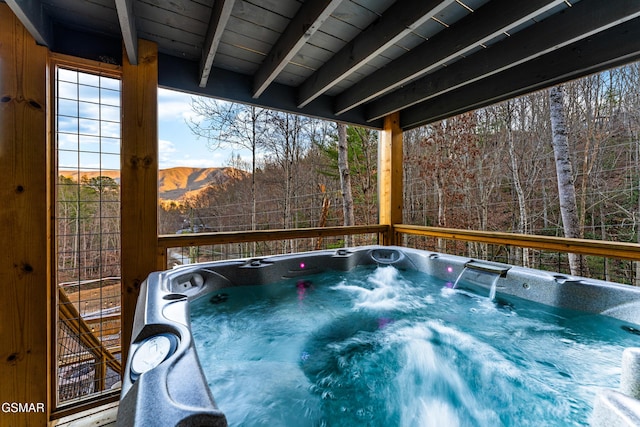 deck with a mountain view, a hot tub, and a forest view