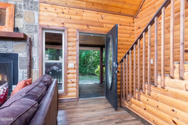 entrance foyer with wood-type flooring, a fireplace, rustic walls, vaulted ceiling, and wooden ceiling