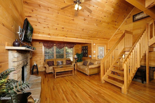 living room featuring wooden walls, high vaulted ceiling, wooden ceiling, light hardwood / wood-style floors, and a stone fireplace