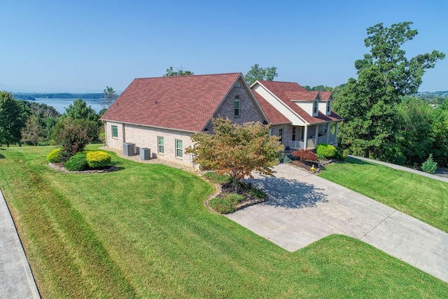 view of front facade with central AC, a water view, and a front lawn