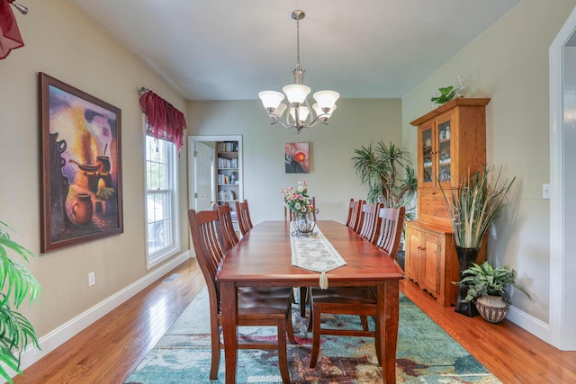 dining room with light wood-type flooring and an inviting chandelier