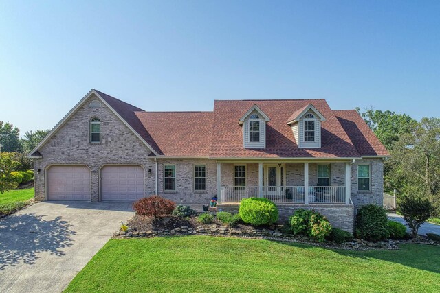 view of front of property with covered porch, a garage, and a front yard