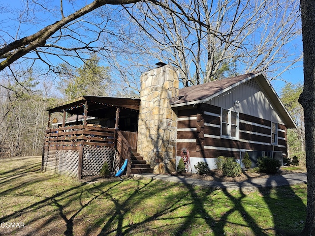 view of side of property featuring roof with shingles, a lawn, a chimney, and log siding