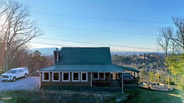 exterior space featuring a porch, metal roof, and a chimney