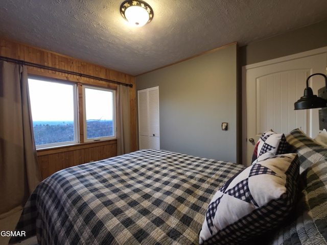 bedroom with wooden walls, a closet, and a textured ceiling