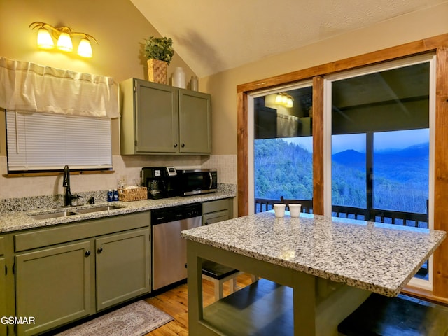 kitchen with light wood-type flooring, a sink, stainless steel appliances, a breakfast bar area, and vaulted ceiling