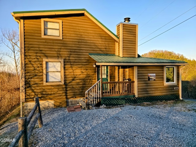 back of house with metal roof and a chimney