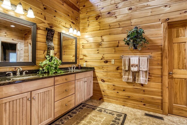 bathroom with tile patterned floors, vanity, and wood walls