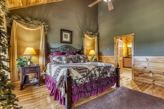 bedroom featuring a towering ceiling, connected bathroom, light hardwood / wood-style floors, and ceiling fan