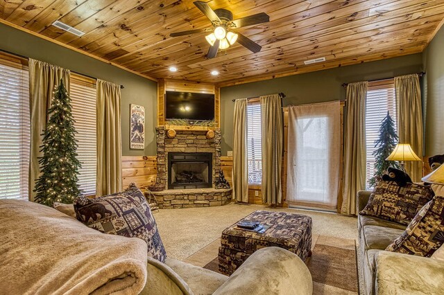 carpeted living room featuring crown molding, ceiling fan, a fireplace, and wooden ceiling