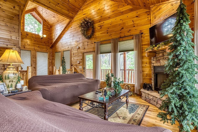 bedroom featuring multiple windows, wooden walls, high vaulted ceiling, and light hardwood / wood-style floors